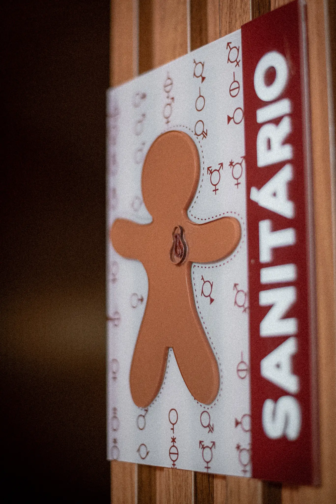 Placa de identificação do banheiro inclusivo com vários símbolos representando gêneros